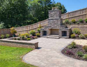 Accessible paver patio with a level surface, outdoor fireplace, seating area and surrounding landscaping